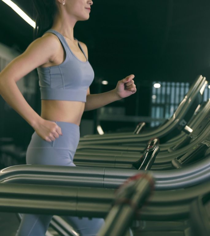 穿运动内衣的年轻女性在健身房使用跑步机