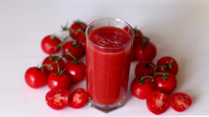 玻璃上有番茄汁在白色背景上，一滴果汁掉入玻璃中。