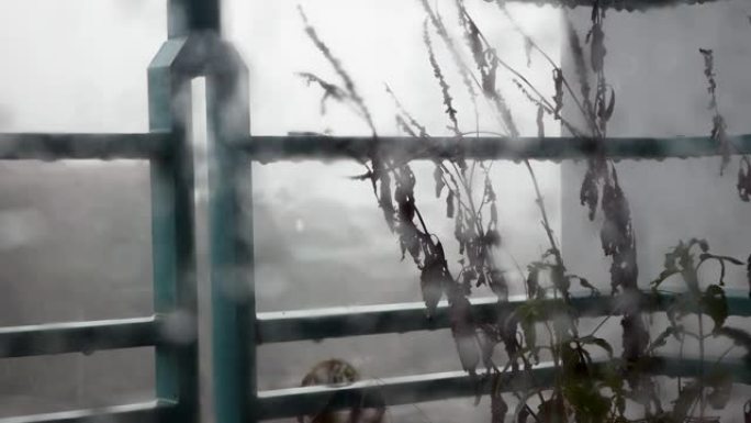 大雨时，水滴从阳台上的栏杆上滴落。穿过泥泞的玻璃。忧郁的概念