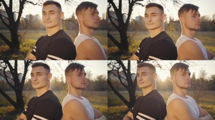 两个年轻的高加索健美运动员站在阳光下看着相机的特写脸。英俊强壮的运动员在秋季公园度过时光。健康的生活