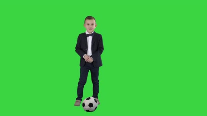 穿着正式西装的男孩在绿屏上踢足球，色键
