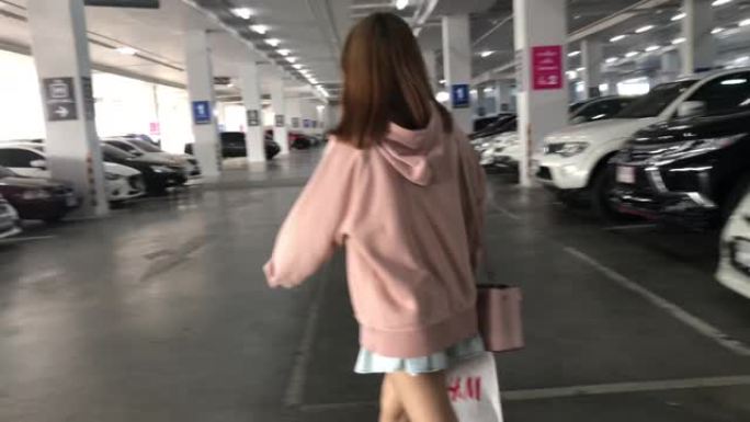亚洲少女带着购物袋在停车场散步