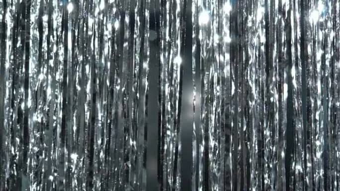 金属丝中的银雨。闪亮的灯光和闪闪发光的粒子中的动态背景。美丽的银色背景，闪亮的银色闪光。节日气氛。圣