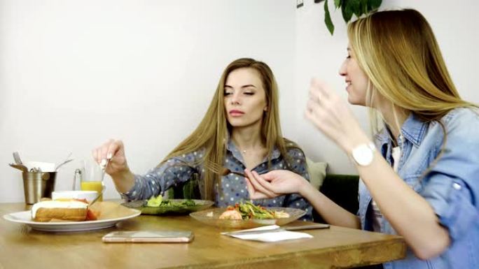食物和饮料。两个迷人的女孩在餐厅吃饭时聊天。4K