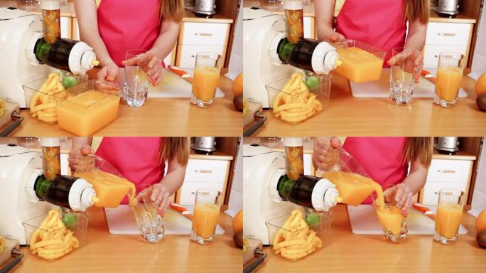 女人在榨汁机中制作橙汁，将饮料倒入玻璃4K