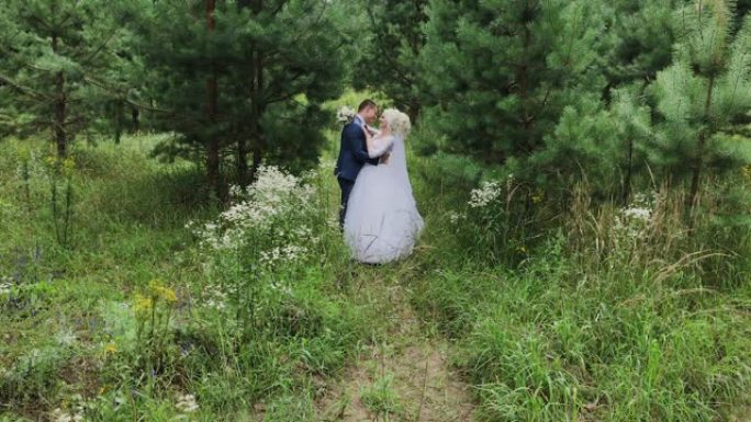 非常漂亮的新娘和新郎在森林里牵手拥抱