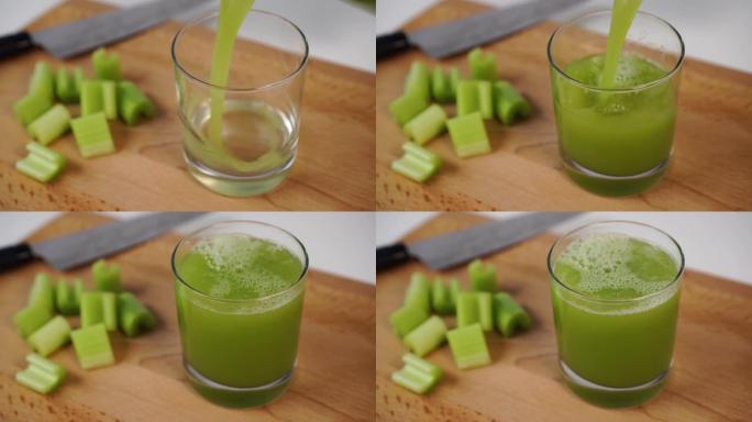 将鲜榨的芹菜汁倒入木制切菜板上的玻璃杯中。用刀和切片多汁的切片
