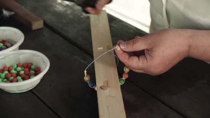 女人的手制作手工制作的珠子手镯的特写镜头