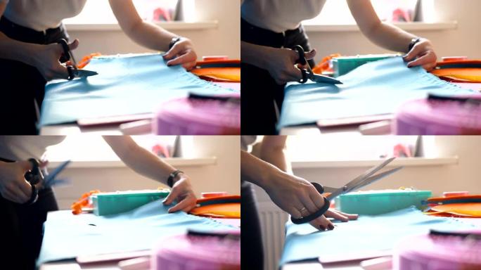 裁缝在桌子上用剪刀剪蓝色布料