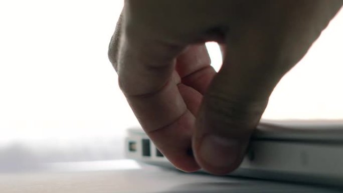 人类的双手拿起存储卡并将其插入笔记本电脑