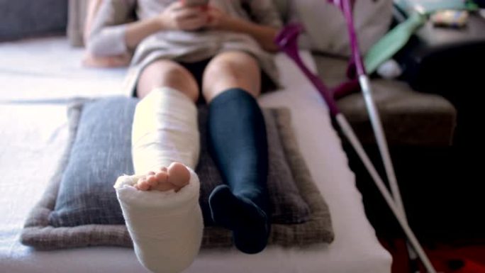 使用智能手机在家中腿部骨折和石膏脚的残疾妇女