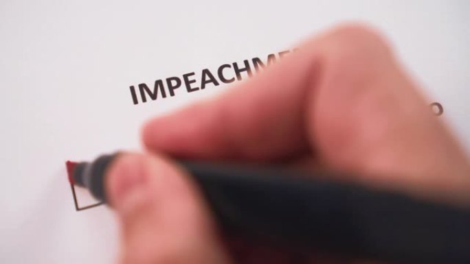 他的手用红色毡尖笔在调查问卷的白色页上的“弹劾”(IMPEACHMENT)一词下面的“是”(YES)