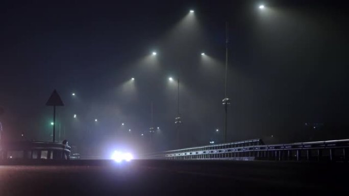 汽车晚上在潮湿的雾气路上行驶。危险的夜间驾驶。高速公路上的灯亮着