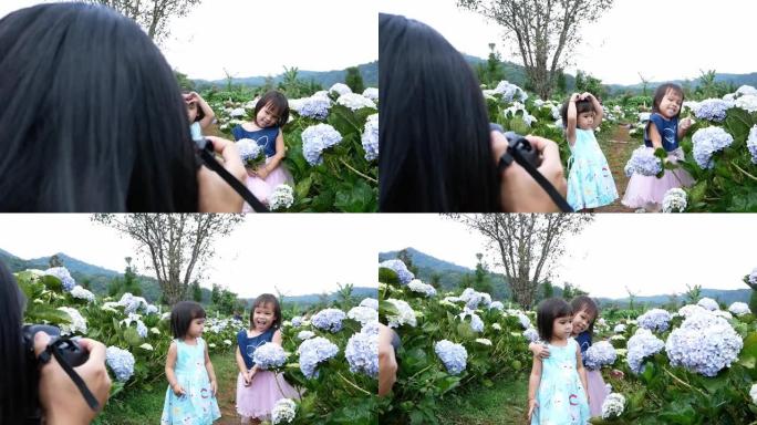 夏天，母亲在绣球花花园里为她的小女儿拍了一张照片。