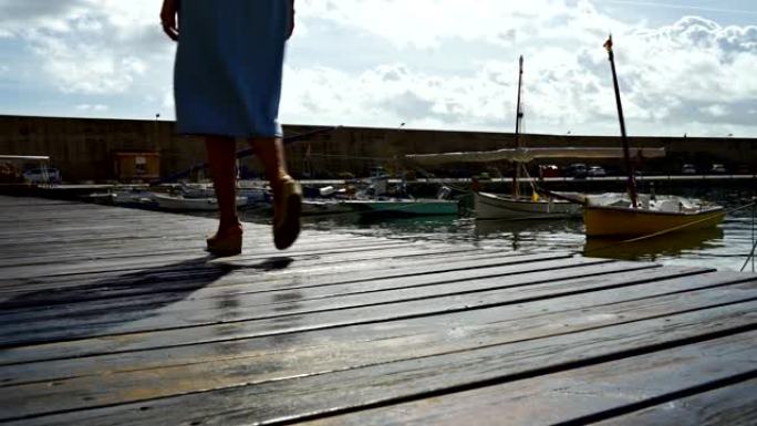 女人的腿在码头的木制人行道上行走