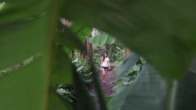 一个女孩沿着城市公园的木制人行道散步。