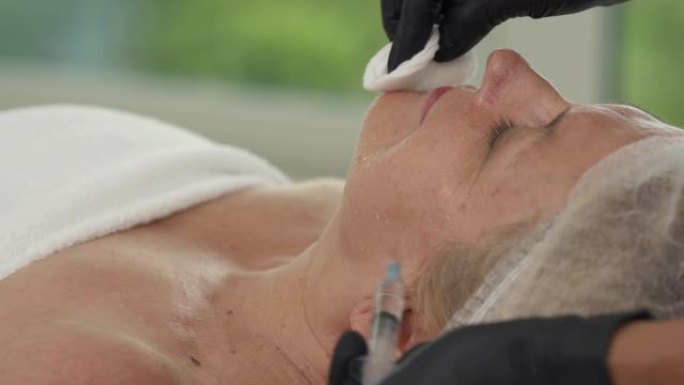 一位专业美容师对高级女性患者进行抗衰老注射的特写演示视频。皮肤振兴概念。中间疗法