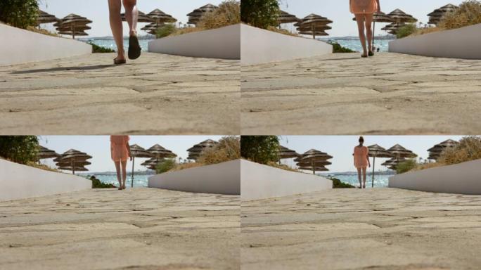 在运动中，一名金发女子在游泳馆和束腰外衣中穿过蔚蓝的地中海沿岸的小路走到海滩，塞浦路斯