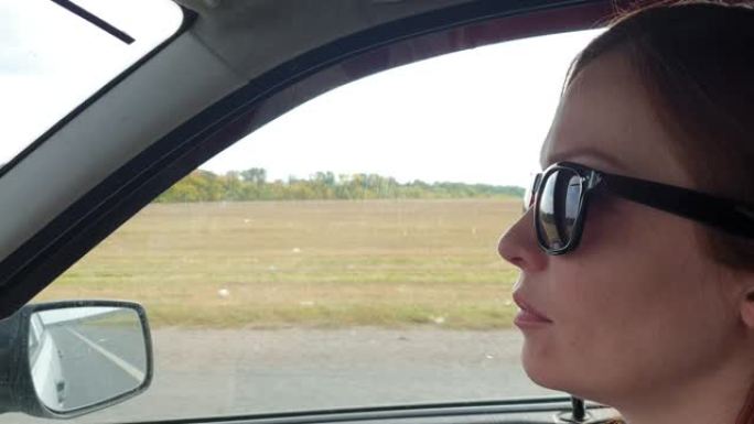 女人戴着墨镜坐在车里，开车旅行