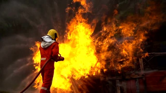 勇敢的消防员的慢动作镜头使用带有螺旋水的消防水带扑灭车祸中的大火