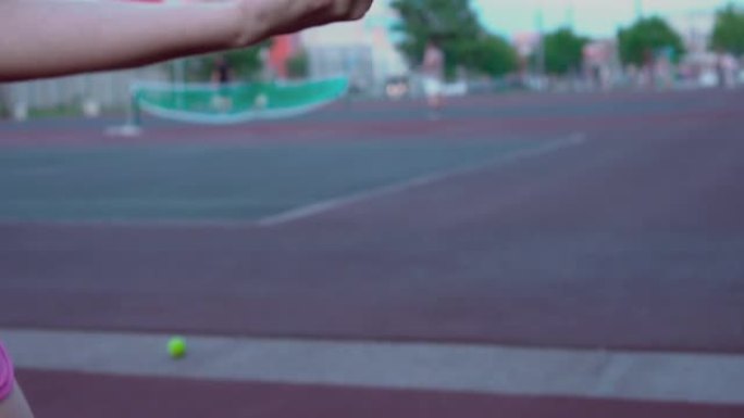 女孩打网球。手姑娘将球抛向空中，然后在训练中接球。