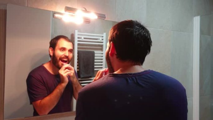 留着胡须的年轻人正在用牙线清洁牙齿。用牙线清洁牙齿的人的特写。口腔保健