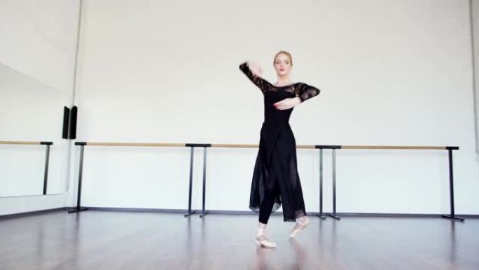 专业芭蕾舞演员穿着黑色蕾丝紧身衣、长裙和脚鞋在芭蕾舞工作室表演舞蹈的平移镜头