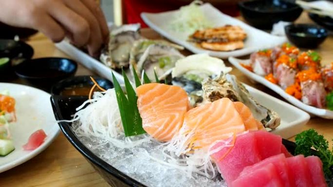 日本生鱼片 (鲑鱼，金枪鱼) 放在盘子里的冰上。平移左枪。