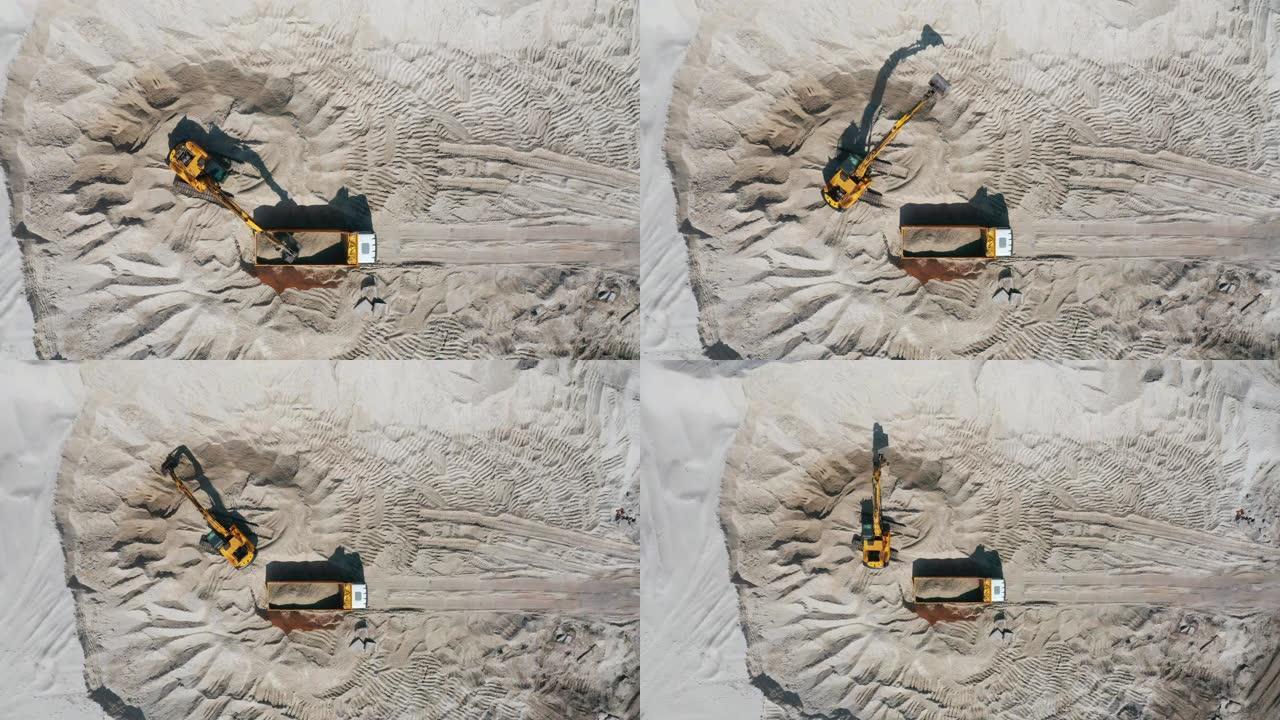 露天采石场推土机将沙子装载到空自卸车中的鸟瞰图。