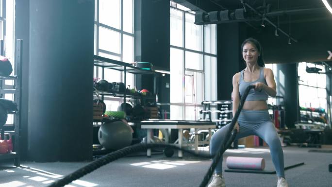 健身房年轻女性使用格斗绳锻炼