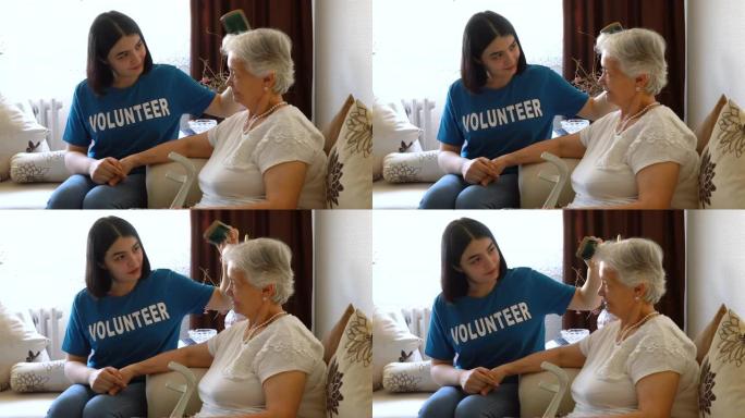 有爱心的年轻女性志愿者在家中梳理老年女士的头发