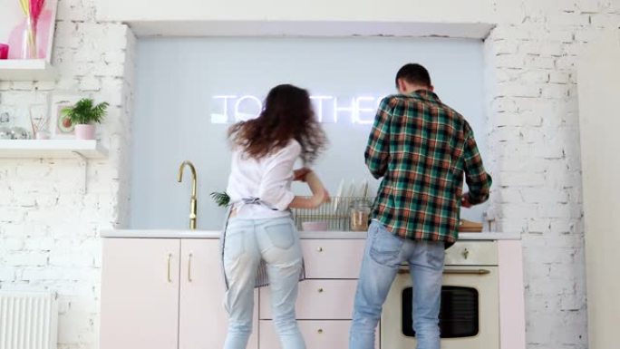 年轻开朗的夫妇一边做饭一边在厨房跳舞。