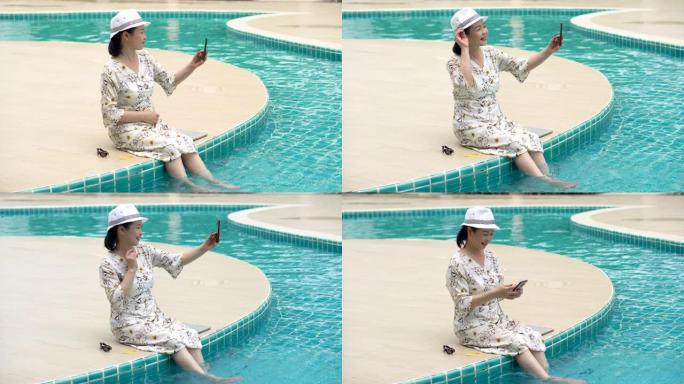 坐在游泳池边的亚洲高级女性户外手机自拍。老太太拍照。退休放松和假期