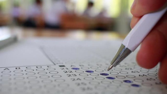 学校或大学生动手考试，用铅笔在课桌上用光学形式的答案纸在教室里做期末考试。教育评估概念