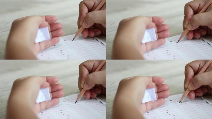 大学生手持铅笔的手在标准化考试表格上选择了多种选择，泰语字母答案气泡和手拿答案纸作弊。