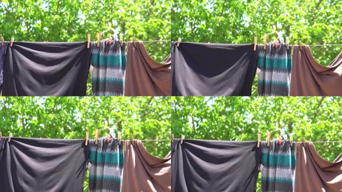 干净的洗过的衣服挂在电线上，带有衣夹和模糊的春季自然背景。