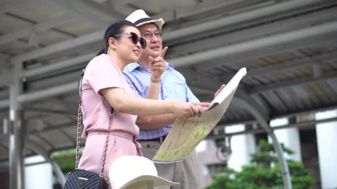 快乐的亚洲老年夫妇游客旅行时看着地图，指着户外城市的目的地。老人旅行者的生活方式。老年妇女度假。老龄