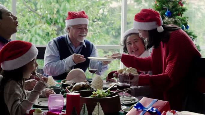 4k慢镜头: 亚洲家庭在家吃饭，喝酒，庆祝圣诞节，新年快乐。其中包括爷爷、奶奶的父母和女儿快乐地坐在