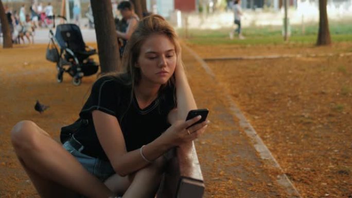 秋天公园里有电话的女人。色彩缤纷的秋季公园中的年轻学生使用手机音频语音信息识别。悲伤的女孩在智能手机