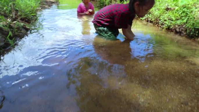 孩子们在溪水中赤脚玩耍，玩泥沙。