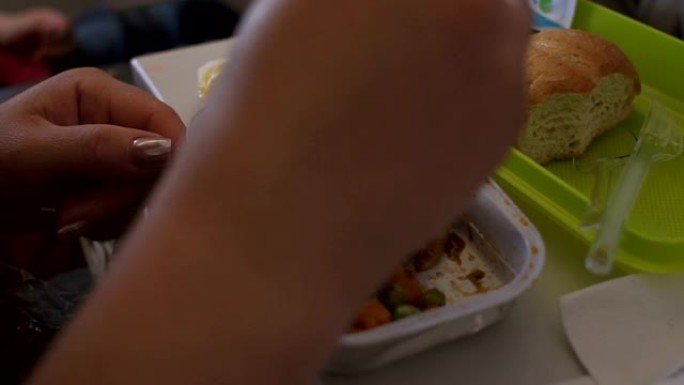 一个女人的特写镜头从飞机上的一个塑料容器里吃午餐。