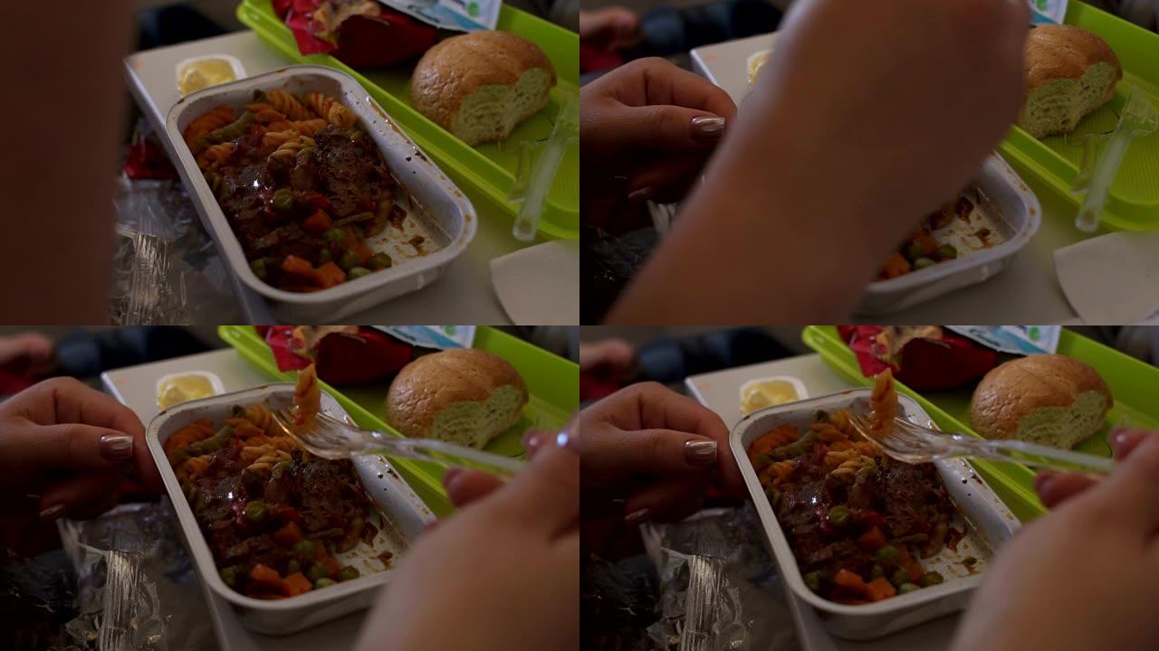 一个女人的特写镜头从飞机上的一个塑料容器里吃午餐。