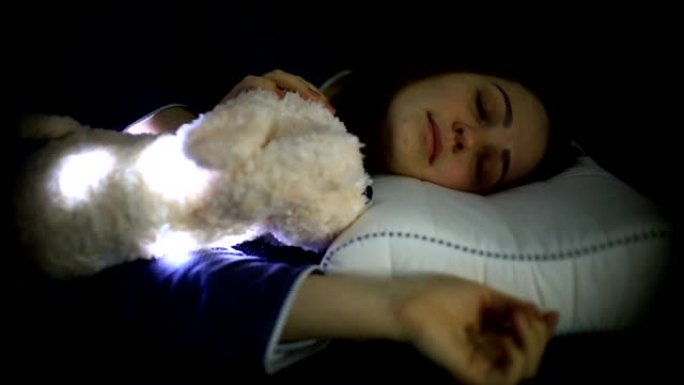 一名年轻女子穿着蓝色衬衫的毛绒玩具睡在矫形枕头上