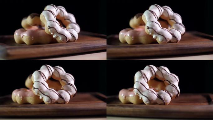 在深色背景的木托盘上转动甜甜圈的镜头，工作室镜头