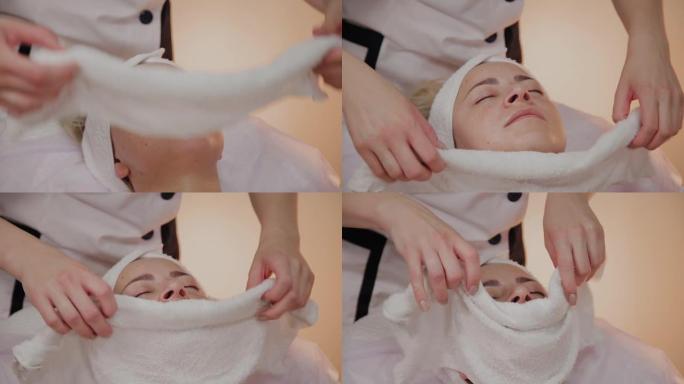 女人在美容师的手术中，脸上带着毛巾