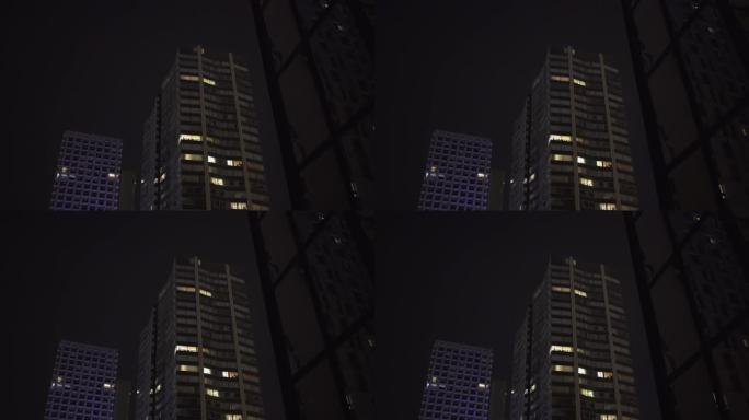 晚上在巴黎商业区用玻璃窗反射摩天大楼，缓慢的稳定运动，反射。带有灯光的未来派现代建筑。4K UHD。