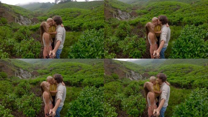 慢动作镜头。年轻夫妇和他们的儿子站在山上的一个大茶园上自拍