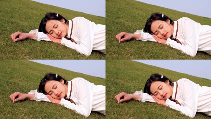 特写一位穿着白衬衫的美丽中国年轻女子的肖像，躺在绿草地上，闭着眼睛，享受春风，做一个好梦，4k镜头，