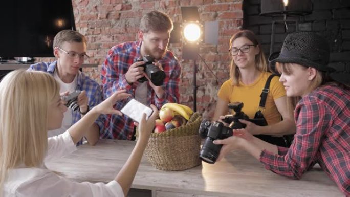 工作室里有设备的大师班，年轻摄影师学习用相机和手机在篮子里拍摄水果的照片