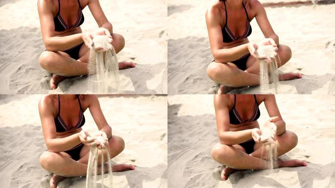 沙滩上穿着比基尼的女性手中的沙子，慢动作